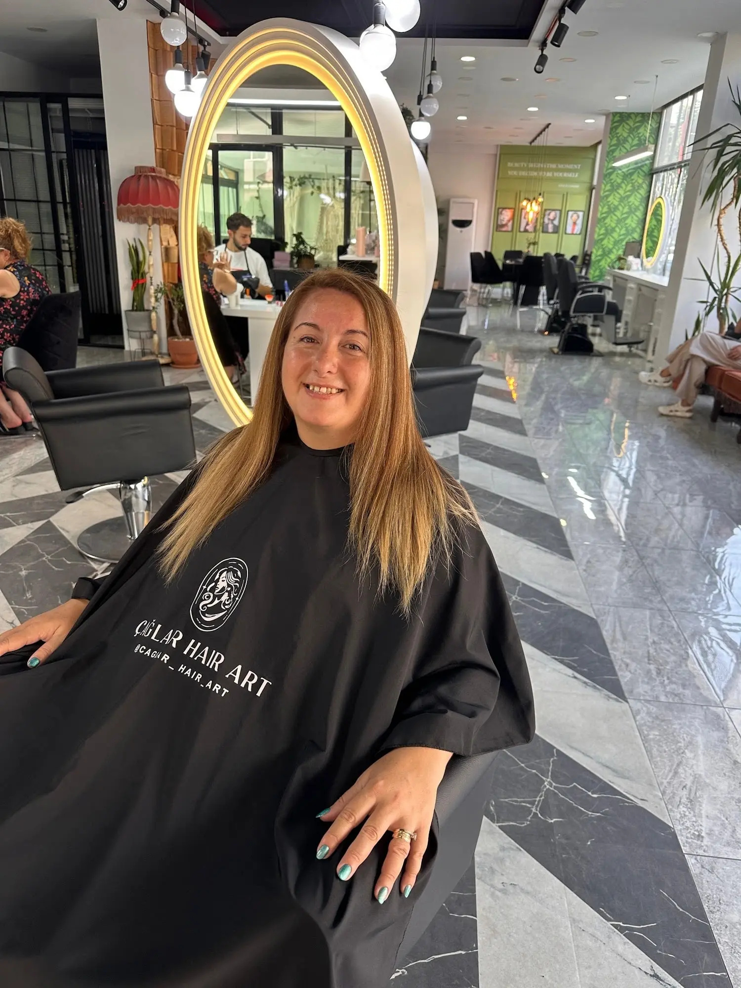 Showmaster Beauty Center salonunda altın ışıklı yuvarlak ayna önünde gülümseyen müşteri, mermer zemin